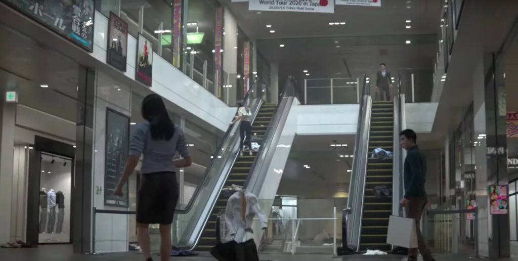 Pessoas em um Shopping e algumas delas desaparecendo e deixando apenas as roupas soltas no chão em Ghostwire Tokyo.