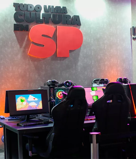 Sala com computadores e a frase "tudo vira cultura em SP" na parede. Secretaria de Cultura de São Paulo investindo em pop e games.